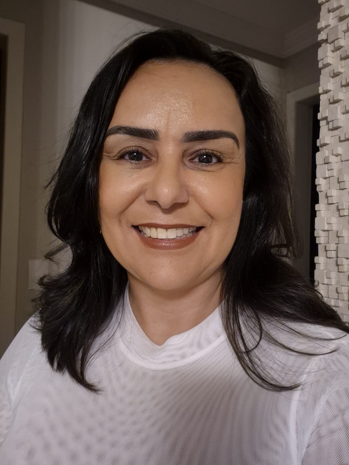 Psicóloga Rosana Azevedo sorrindo, com uma parede texturizada ao fundo.